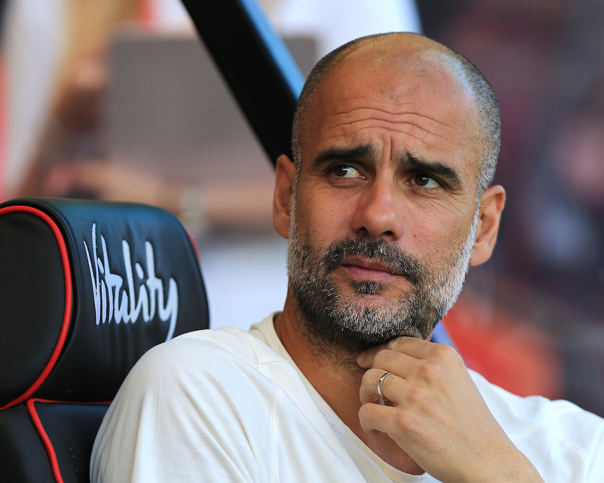 Pep Guardiola sits on the bench