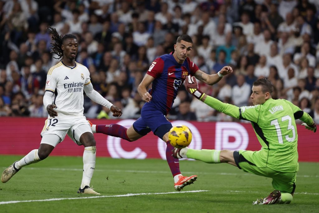 Real Madrid's goalkeeper Lunin (R) in action against FC Barcelona's Spanish striker Ferran Torres (C) during the LaLiga soccer match between Real Madrid and FC Barcelona, at the Santiago Bernabeu Stadium.