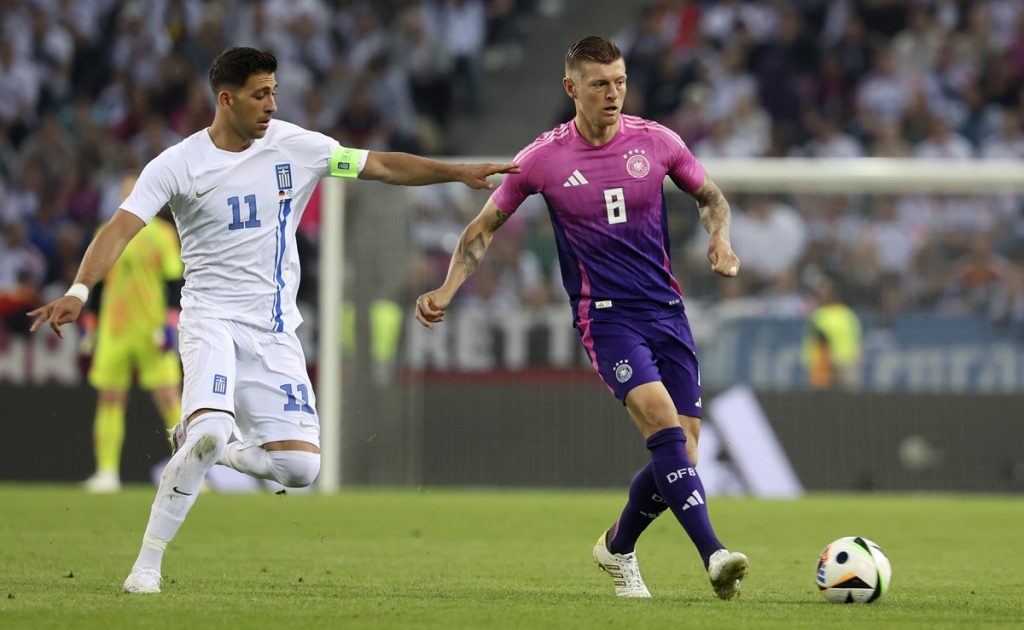 Toni Kroos of Germany (R) in action against Anastasios Bakasetas of Greece (L) during the international friendly soccer match between Germany and Greece in Moenchengladbach, Germany, 07 June 2024.